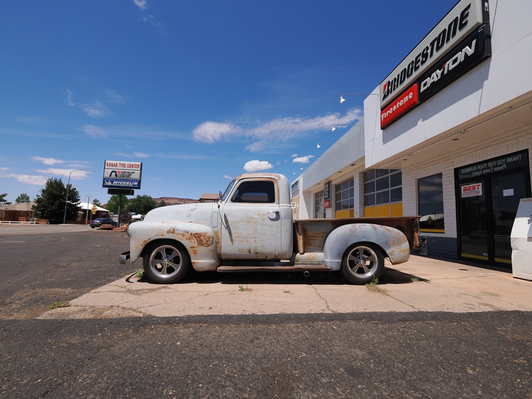 old-white-pickup-truck-parked-outside-building-3i81zythife